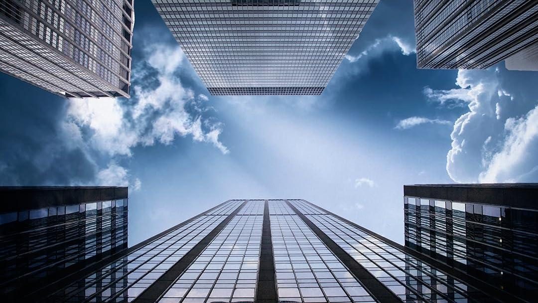Modern glass office towers photographed looking upward against a blue sky